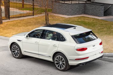 Novosibirsk, Rusya - 01 Mayıs 2024: Beyaz Bentley Bentayga, bir yaz günü caddeye park etmiş, şehrin arka planına,