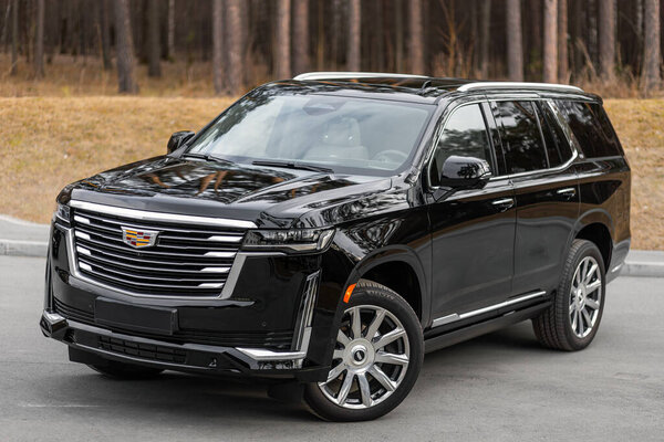 Novosibirsk, Russia -  April 30  , 2024:  black  Cadillac Escalade 600 ,  front  view. SUV   car  against park  in  summer time 