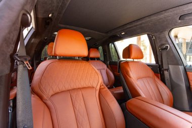 Novosibirsk, Rusya - 15 Mayıs 2024: siyah BMW X7, arka planda emniyet kemerleriyle arka planda bulunan kahverengi deri koltuklar. Lüks araba iç mekanı.