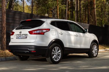 Novosibirsk, Rusya - 15 Mayıs 2024: Beyaz Nissan Kashqai yaz mevsiminde park halinde, arka manzara