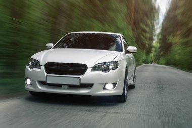 Park yolunda giden beyaz bir araba, ön manzara.