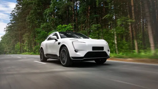 stock image A white  new  SUV  is driving along a highway in the forest with a blurred background. Fast driving