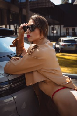 Lüks bir arabanın reklamını yapmak için mayo giymiş genç kadın fitness mankeni. 