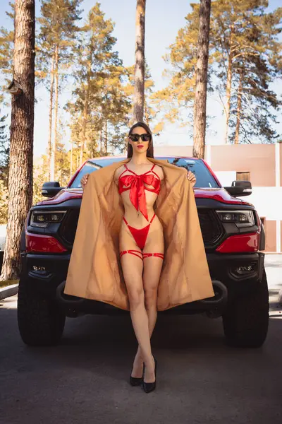 stock image Sensual brunette woman in red lingerie and sunglasses posing against the background of a luxury pickup car