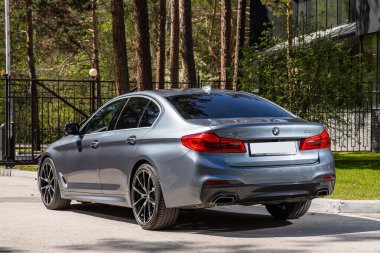 Novosibirsk, Rusya - 10 Temmuz 2024: BMW 5 serisi, sıcak bir yaz gününde park arkaplanına karşı sokağa park edildi 