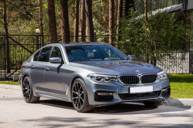 Novosibirsk, Rusya - 10 Temmuz 2024: BMW 5 serisi, sıcak bir yaz gününde park arkaplanına karşı sokağa park edildi 