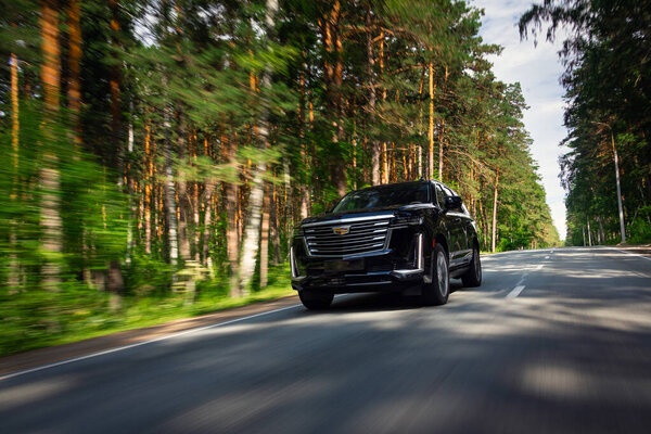 Novosibirsk, Russia -  August  05, 2024: black  Cadillac Escalade 600 SUV  driving  in  park, side view