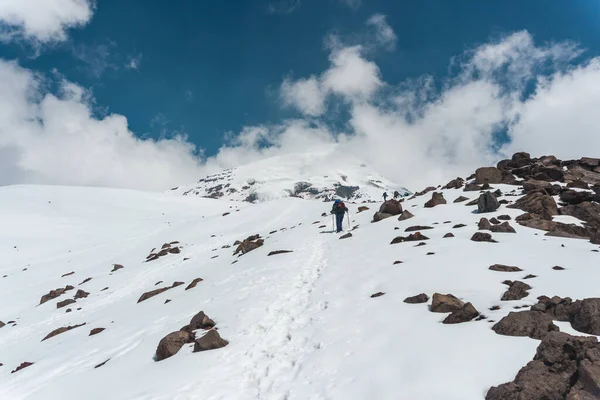group of mountaineers climbs to the top of a snow-capped mountain