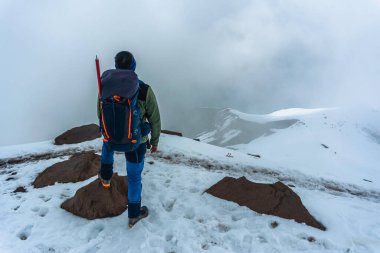 Dağlarda trekking sırt çantası olan adam. Soğuk hava, tepelerde kar.