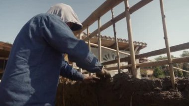 hands a man building a wall with reed and mud