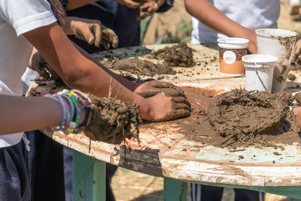 a hands of children playing with mud, ecological construction