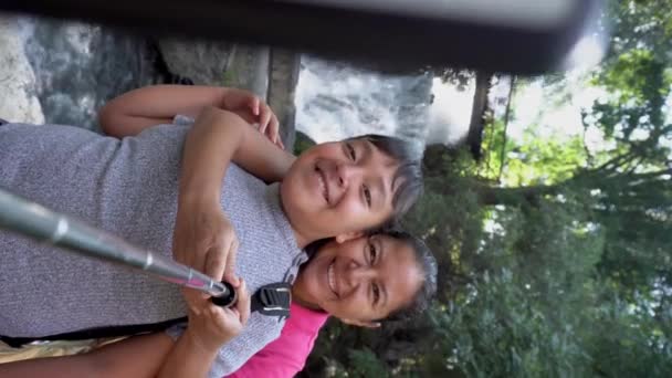 評価された家族のママ 母と娘はバックドロップとして雄大な滝でセルフィーをスナップ — ストック動画