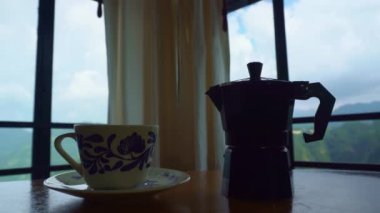 Kahve fincanının zaman aşımı ve bir İtalyan kahve makinesinin pencere önünde durması.