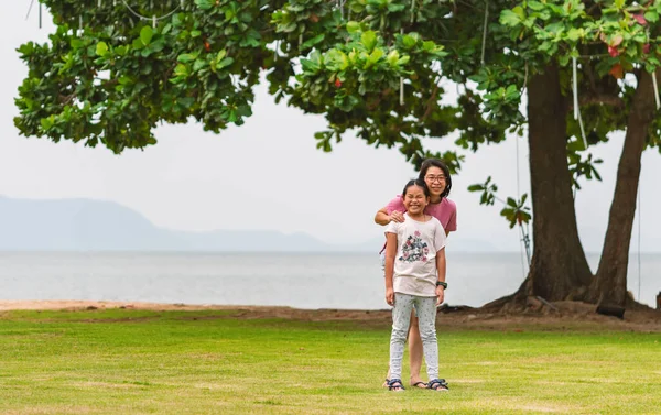 肖像画亚洲的母亲和小女儿站在沙滩边的草地上 笑容满面 山的宽阔图像背景 文字空间 — 图库照片