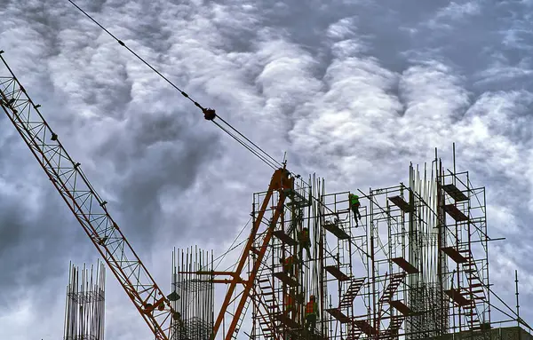 stock image Landscape image of workers working in a construction site on the top of a building, massive clouds sky background.