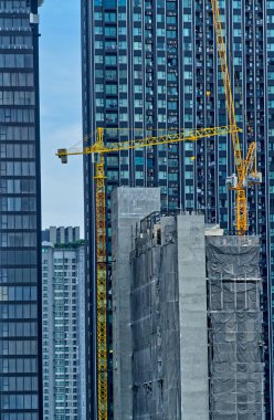 Bangkok, Tayland - 07 Şubat 2022: Konut inşaatı, bir binanın tepesindeki vinç, yüksek apartman binalarıyla çevrili.