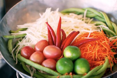 Som Tum 'un taze malzemelerini ya da Tayland yemeklerinin popüler sağlıklı menüsündeki baharatlı papaya salatasını kapat. Taze kırmızı biber, domates, limon dilimlenmiş havuç, doğranmış çiğ papaya, çalı fasulyesi.