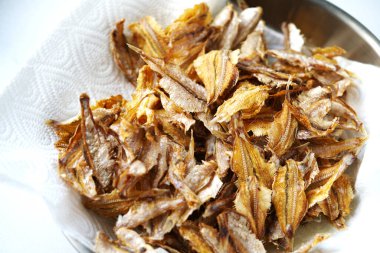 Pişirme yağını emmek için beyaz mutfak havlusu kağıdında kızartılmış küçük balıkları kapat, yukarıdan bak..