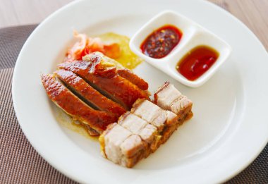 Çin usulü kızarmış ördek ya da Pekin usulü ördek ve kızarmış domuz etini birlikte beyaz bir tabakta yakın. Küçük porsiyon Çin usulü ördek ve kızarmış domuz eti. Doğal ışık görüntüsü.