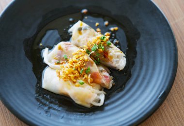 Akıntıya kapılmış Çin eriştelerini doğal ışık ile siyah tabakta yuvarla, Çin eriştelerini yakın akışına bırak, üzerine bol yağda kızartılmış sarımsak ve taze soğan koy..