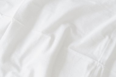 Dalgalanmış beyaz ipek kumaşın soyut arkaplanı yumuşak dalgalarla örtülmüş beyaz kumaş boş yatak örtüsü. Kapat..