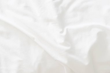 Dalgalanmış beyaz ipek kumaşın soyut arkaplanı yumuşak dalgalarla örtülmüş beyaz kumaş boş yatak örtüsü. Kapat..