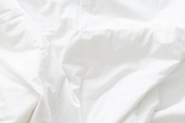 Dalgalanmış beyaz ipek kumaşın soyut arkaplanı yumuşak dalgalarla örtülmüş beyaz kumaş boş yatak örtüsü. Kapat..