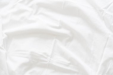 Dalgalanmış beyaz ipek kumaşın soyut arkaplanı yumuşak dalgalarla örtülmüş beyaz kumaş boş yatak örtüsü. Kapat..