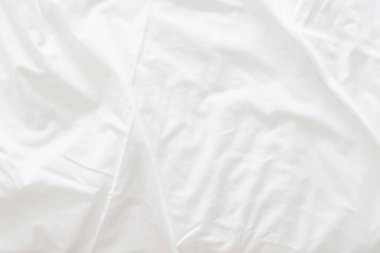 Dalgalanmış beyaz ipek kumaşın soyut arkaplanı yumuşak dalgalarla örtülmüş beyaz kumaş boş yatak örtüsü. Kapat..
