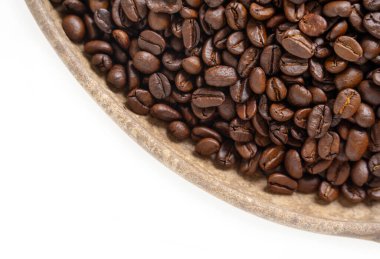 Kahve çekirdekleri ve beyaz üzerine ahşap tabak. Kahverengi kahve çekirdeklerinin üst görüntüsü. Kapat..