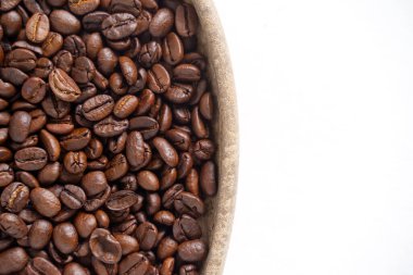 Kahve çekirdekleri ve beyaz üzerine ahşap tabak. Kahverengi kahve çekirdeklerinin üst görüntüsü. Kapat..