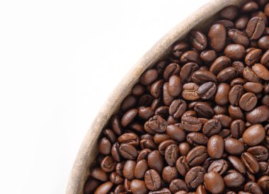 Kahve çekirdekleri ve beyaz üzerine ahşap tabak. Kahverengi kahve çekirdeklerinin üst görüntüsü. Kapat..