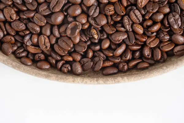 Kahve çekirdekleri ve beyaz üzerine ahşap tabak. Kahverengi kahve çekirdeklerinin üst görüntüsü. Kapat..