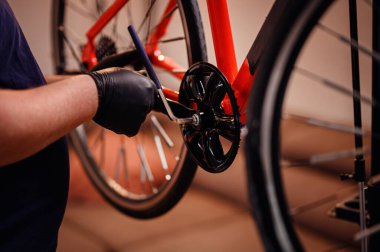 Eldivenli eller, krank kolunu kırmızı motorların alt ayraçına takmak için bir araç kullanır, hassas mekanik montaja odaklanır.