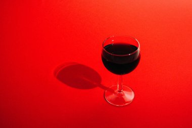 Kırmızı arka planda kırmızı şarap kadehi.