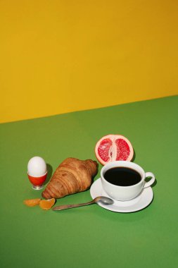Sarı arka planda kruvasan, kahve ve kruvasanla kahvaltı..