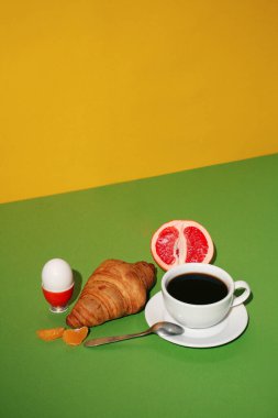 Kahvaltıda kruvasan ve sarı arka planda kahve.