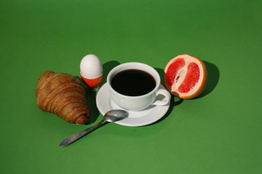 Kahvaltını kahve ve kruvasanla yeşil arka planda yap.