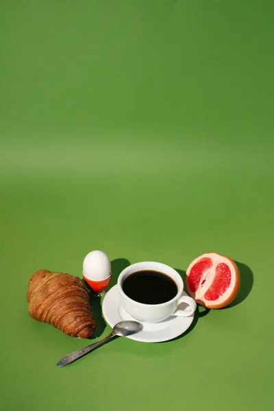 breakfast, cup of coffee and croissant on a green background