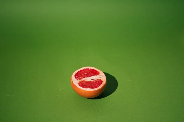 a piece of red grapefruit on a green background
