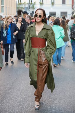 MİLAN, İTALYA 21 Eylül 2022: Zeytin yeşili trençkotlu ve kahverengi deri pantolonlu kadın Alberta Ferretti moda defilesi, Milan Moda Haftası tarzı