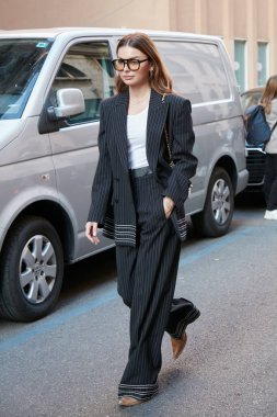 MİLAN, İTALYA 21 EYLÜL 2022: Siyah beyaz çizgili ceketli ve pantolonlu kadın Alberta Ferretti moda defilesinden önce yürüyor, Milan Moda Haftası tarzı.