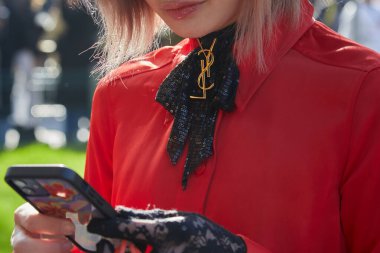 MILAN, ITALY - JANUARY 14, 2023: Woman with black sequin ribbon with golden Yves Saint Laurent logo before Emporio Armani fashion show, Milan Fashion Week street style