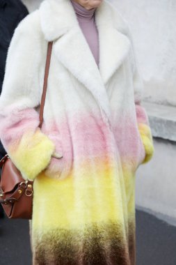 MILAN, ITALY - JANUARY 15, 2023: Woman with fur coat with soft gradient in pale colors before Prada fashion show, Milan Fashion Week street style