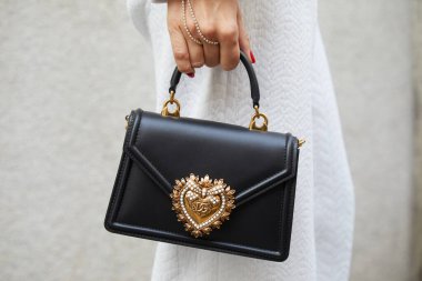 MİLAN, İTALYA 23 Şubat 2023: Dolce ve Gabbana çantalı kadın Genny defilesinden önce altın kalpli, Milan Moda Haftası tarzı