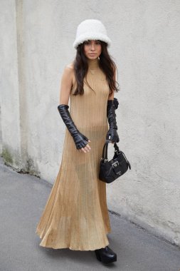 MİLAN, İtalya - 23 Şubat 2023: Beyaz kürk şapkalı, bej elbiseli ve siyah deri eldivenli kadın Prada defilesinden önce, Milan Moda Haftası tarzı