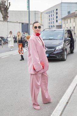 MİLAN, İTALYA - 23 Şubat 2023: Prada defilesinden önce pembe ceketli, pantolonlu ve kırmızı çiçek kolyeli kadın, Milan Moda Haftası tarzı