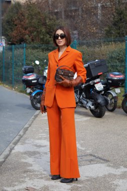 MILAN, İtalya - 25 Şubat 2023: Turuncu ceketli, pantolonlu ve kahverengi deri eldivenli Ludovica Ragazzo Ferragamo defilesinden önce, Milan Moda Haftası tarzı