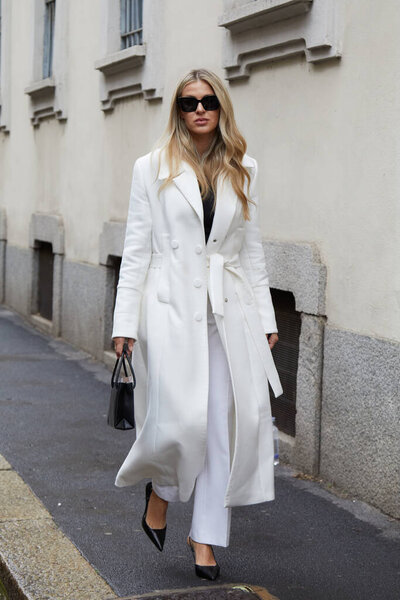 MILAN, ITALY - FEBRUARY 26, 2023: Woman with white coat and trousers before Luisa Spagnoli fashion show, Milan Fashion Week street style