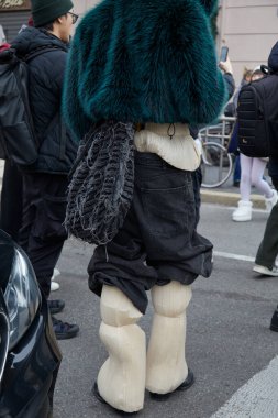 MILAN, İTALYA 14 Ocak 2024: Yeşil kürklü adam, beyaz pantolon ve siyah kot pantolon K-Way defilesinden önce, Milan Moda Haftası tarzı